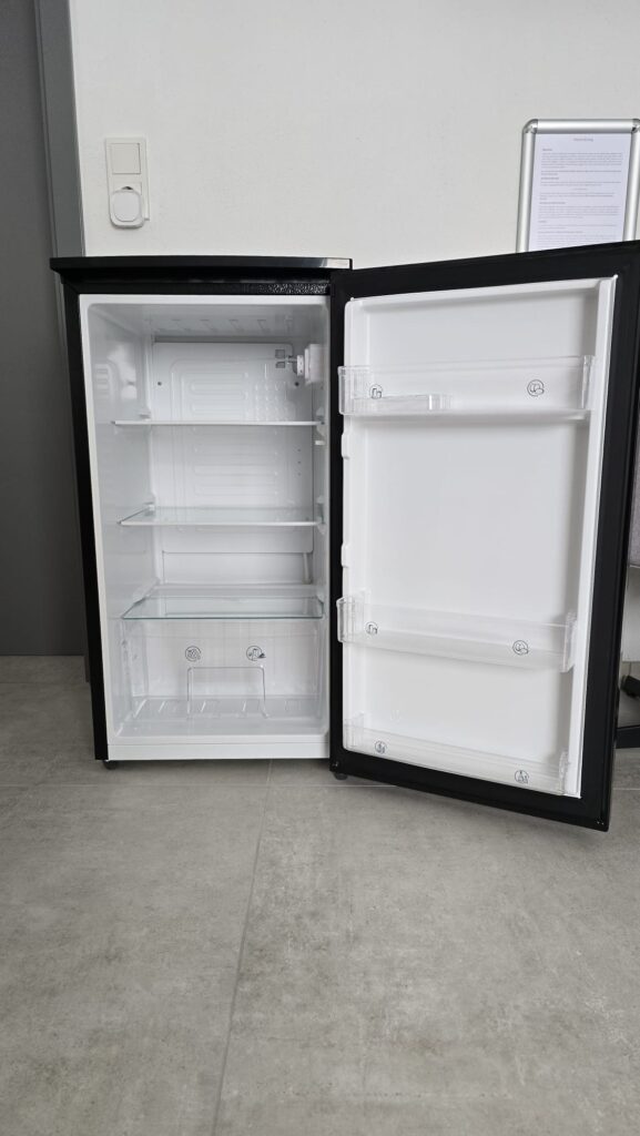 Geöffneter Kühlschrank mit Glasböden und Türfächern im Zimmer